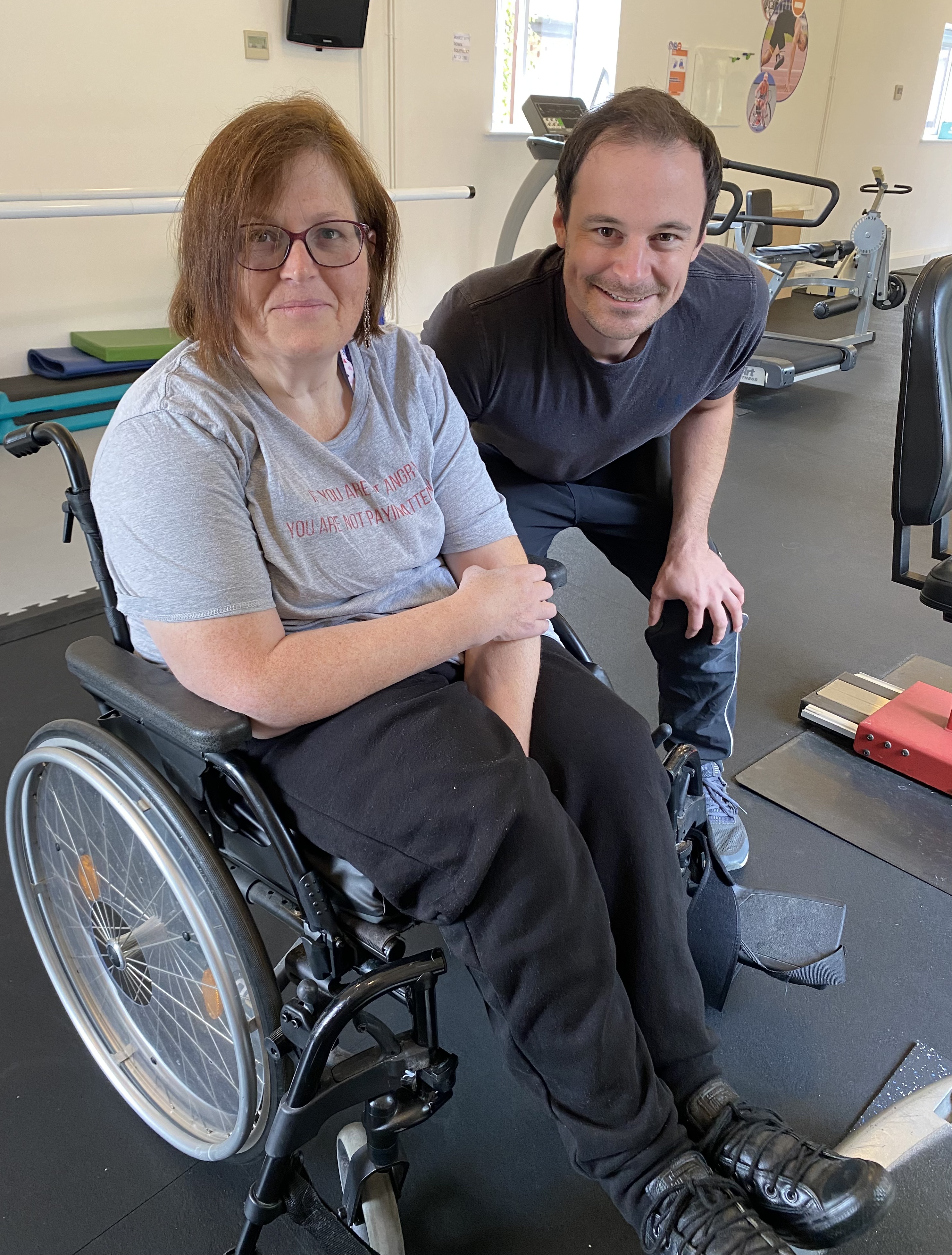 Sam C. with Matt Brinkley in the Therapy Gym, showing the welcoming and supportive environment for people with mobility challenges